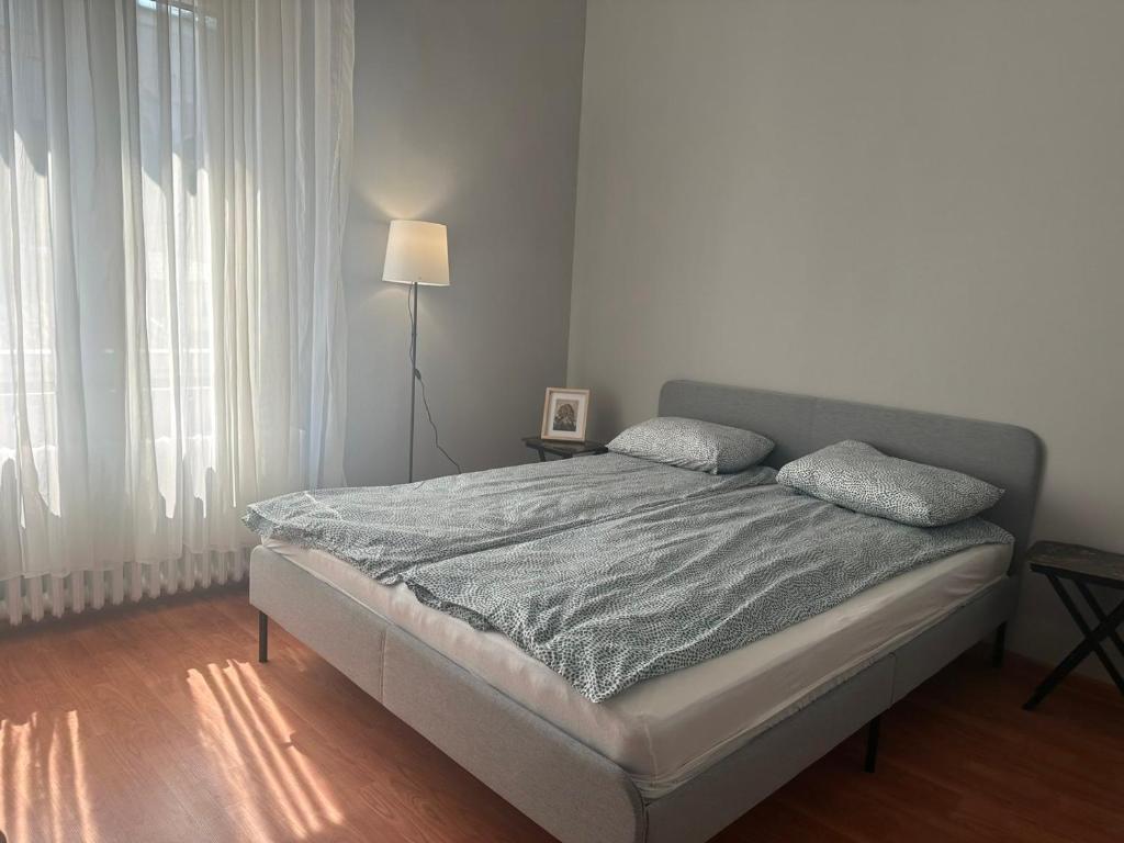 a bed in a white room with a lamp and windows at EVA Apartment in Novi Sad
