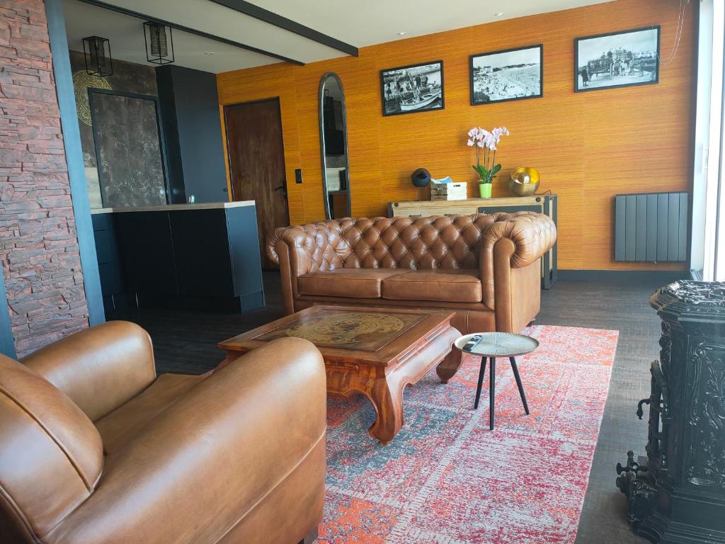 een woonkamer met bruine leren banken en een tafel bij This one in Concarneau