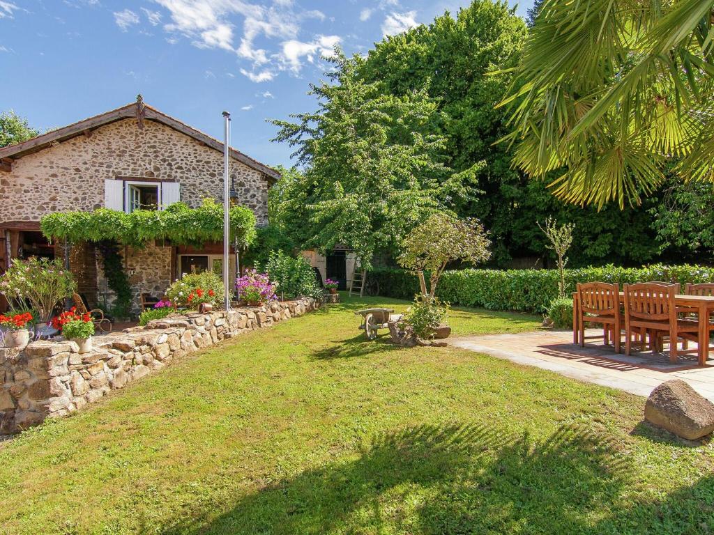 a garden with a table and chairs and a building at Romantic cottage with shared swimming pool in Roussines
