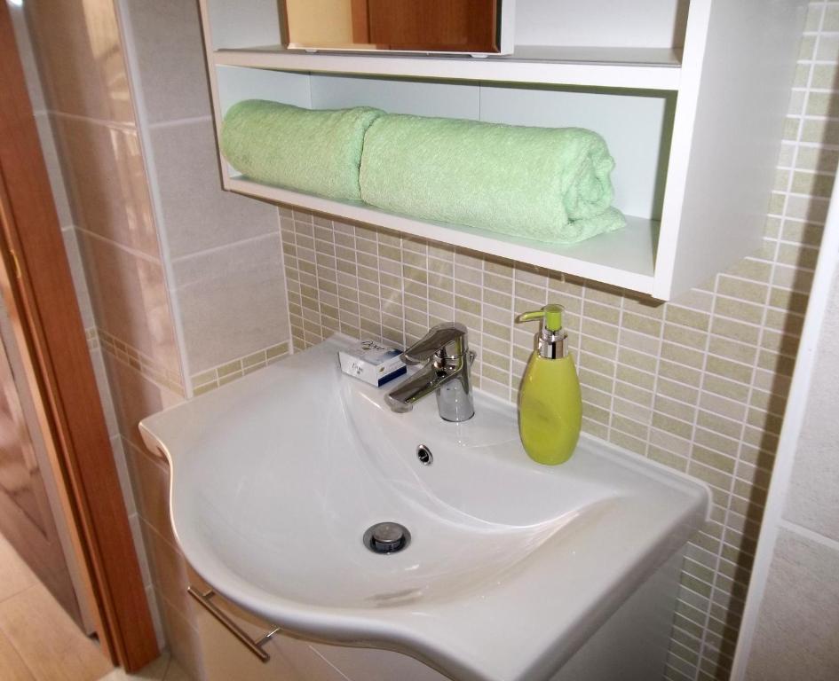 a white sink in a bathroom with a green towel at Apartment Vrančić in Šibenik