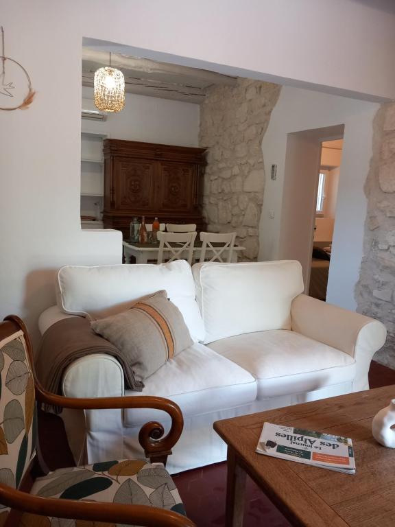 - un salon avec un canapé blanc et une table dans l'établissement Le Petit Mas des Alpilles en Provence, à Saint-Étienne-du-Grès