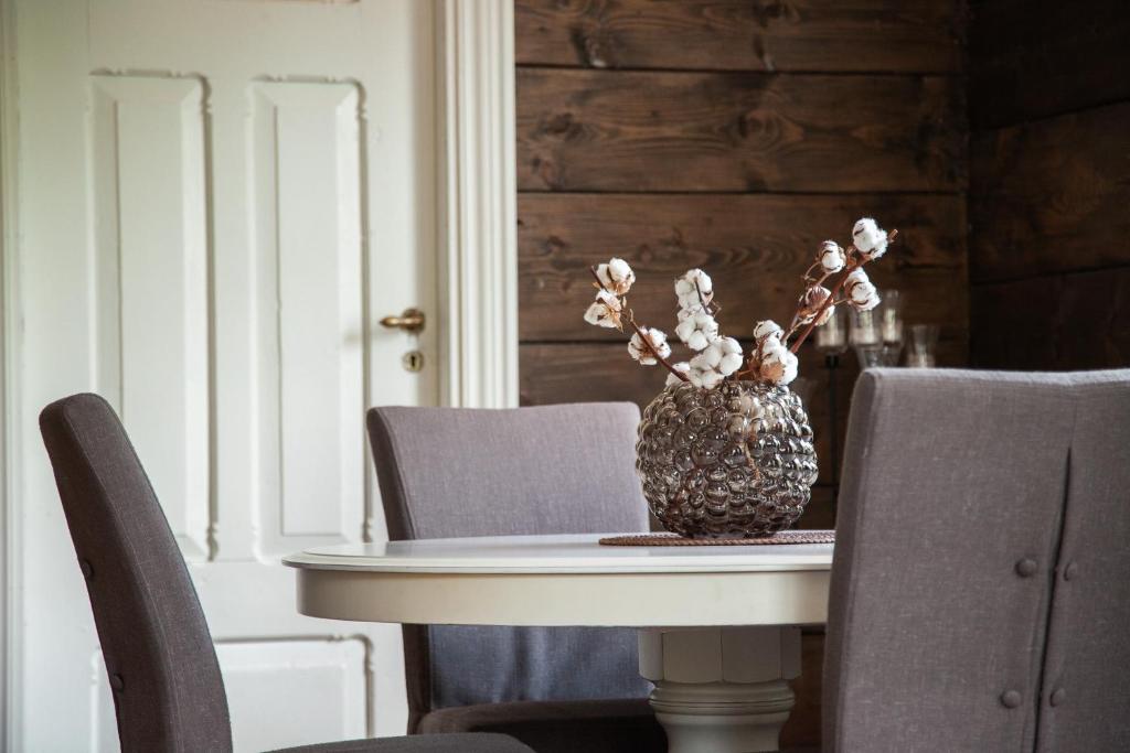 stół z krzesłami i wazon z kwiatami w obiekcie Tuftegarden w mieście Viksdalen