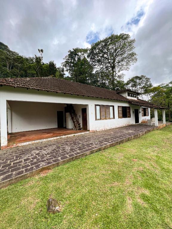 a white house with a porch and a yard at Chale das hortensias in Petrópolis