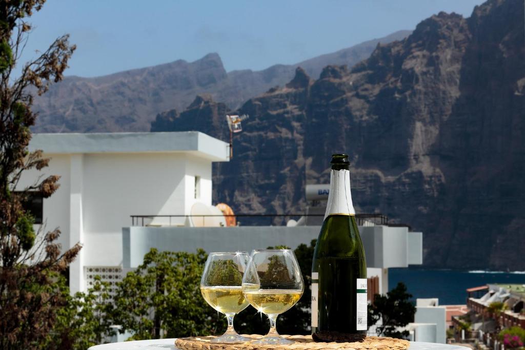 Una botella de vino y dos copas en una mesa. en One-bedroom with views of Los Gigantes en Santiago del Teide