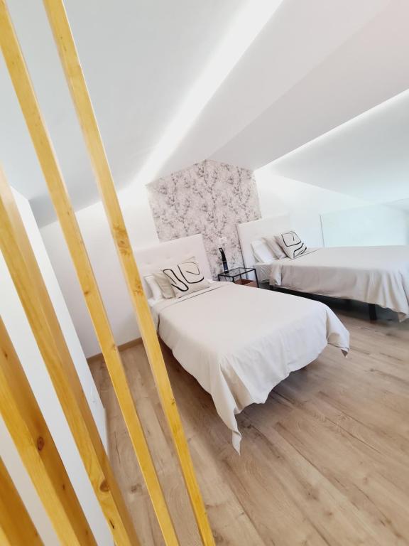 two beds in a room with white walls and wooden floors at INFINITY VIEW in Playa del Aguila