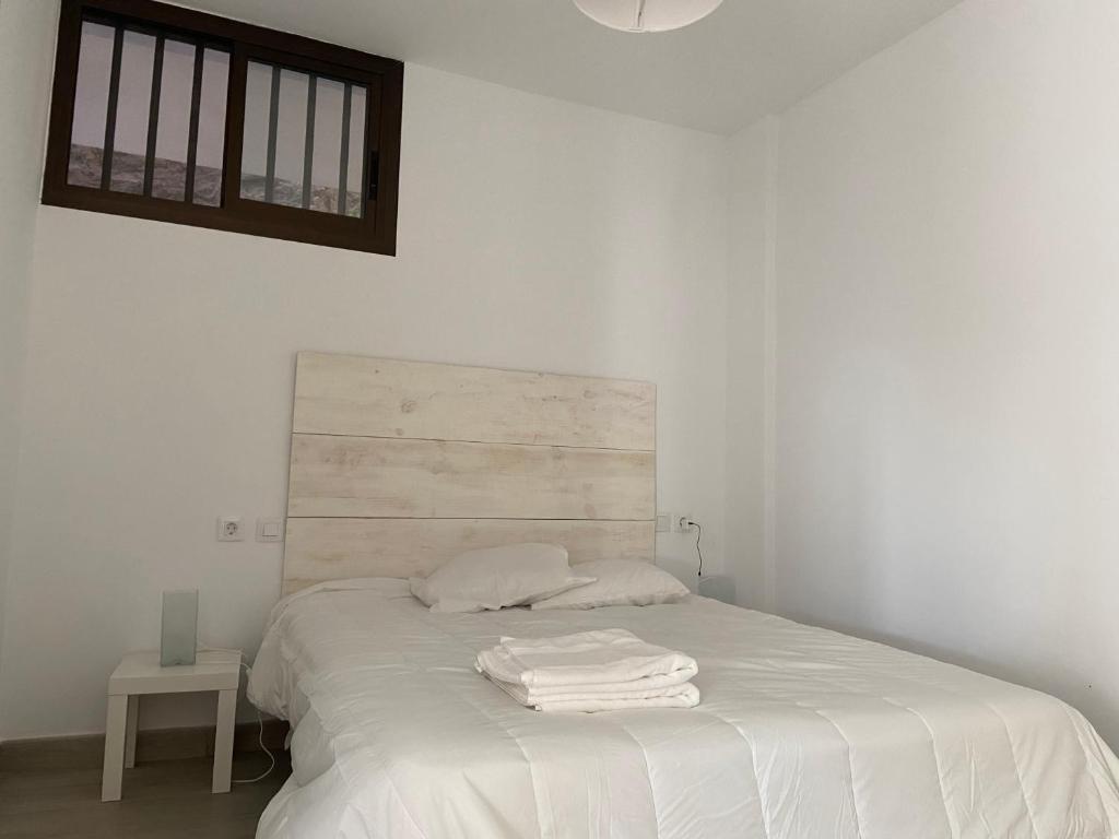Una cama blanca con dos toallas blancas. en Sunhome apartment, en Mogán