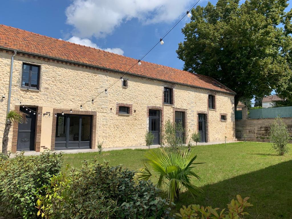 un antiguo edificio de ladrillo con un patio verde en LE CLOS DES LYS - Chambres avec jacuzzi - Nemours, en Treuzy-Levelay