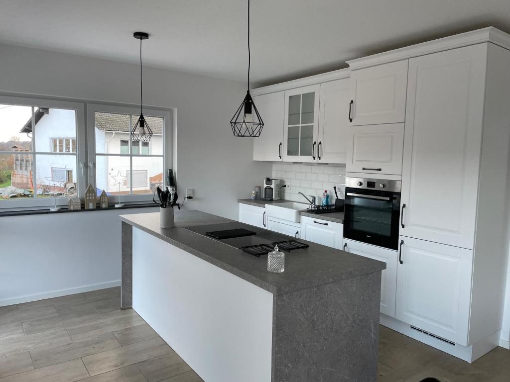 a kitchen with white cabinets and a black counter top at Hochwaldblick in Glan-Münchweiler