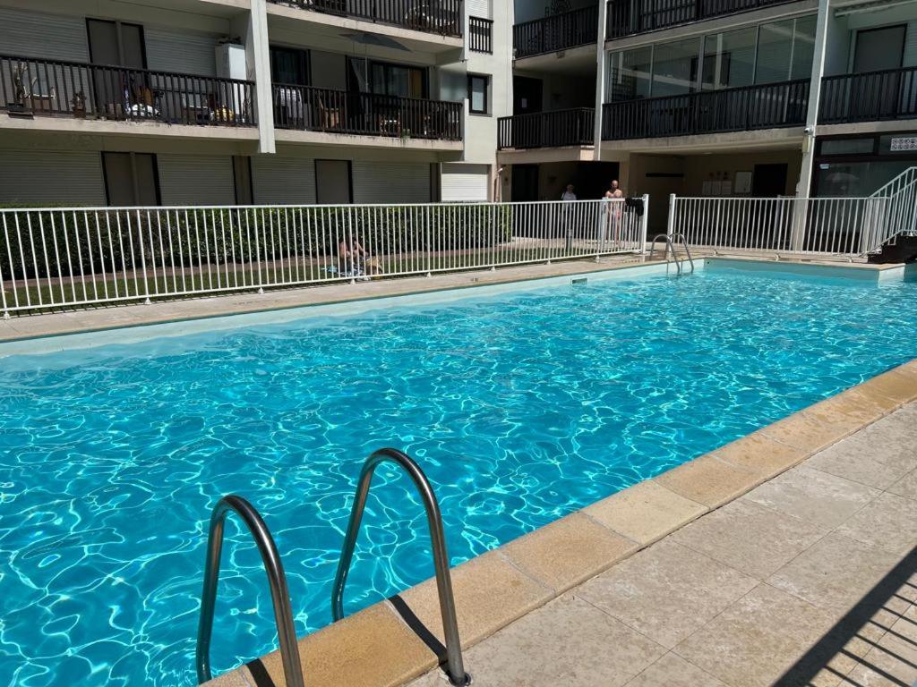 une grande piscine bleue devant un immeuble dans l'établissement LE COSY avec piscine, balcon et parking, à Trouville-sur-Mer