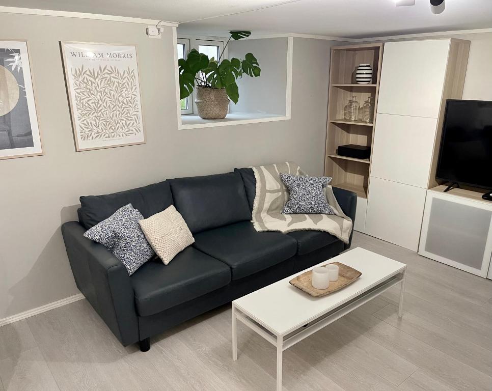 a living room with a black couch and a coffee table at One bedroom basement apartment in the city in Tromsø