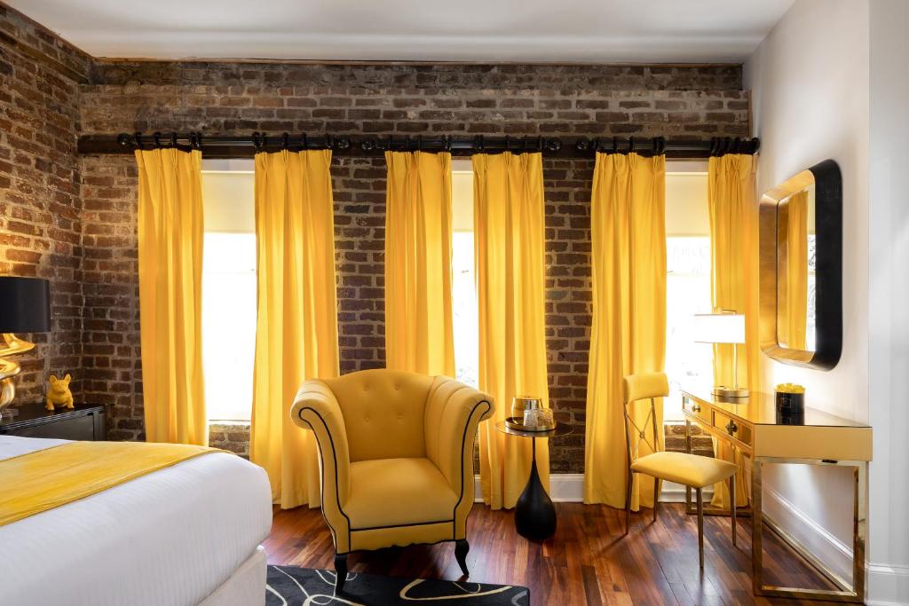 a bedroom with a bed and a chair and a desk at The Vendue, Downtown Art Hotel in Charleston