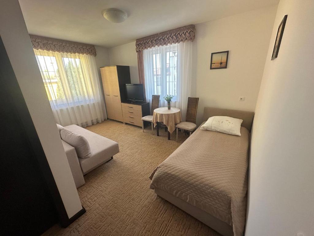 1 dormitorio con cama, sofá y TV en Villa California en Darlowko
