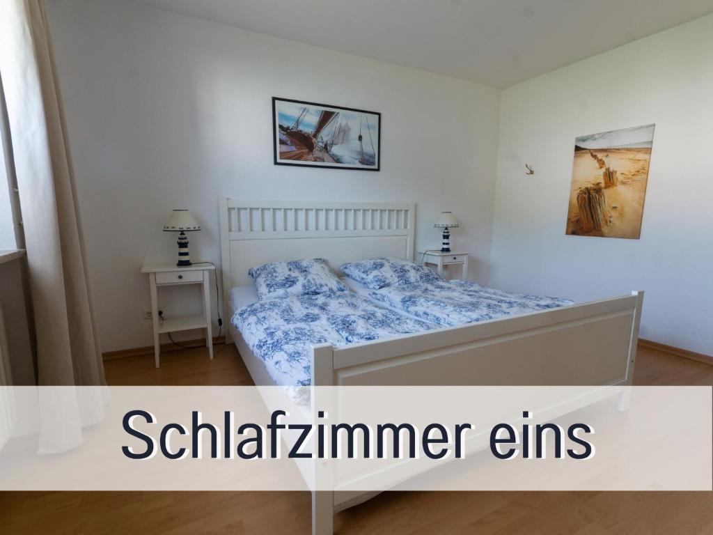 a white bedroom with a bed and two tables at FeWo Wichmanninklusive Strandkorb am Meer free WLAN bis 6 Personen, Platz für Ihre Fahrräder in Grömitz