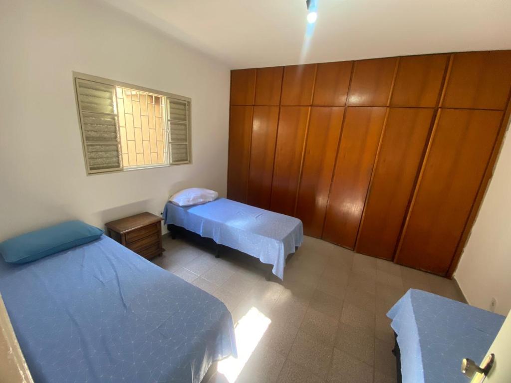 a room with two beds and a wooden cabinet at Casa Comendador in Uberlândia