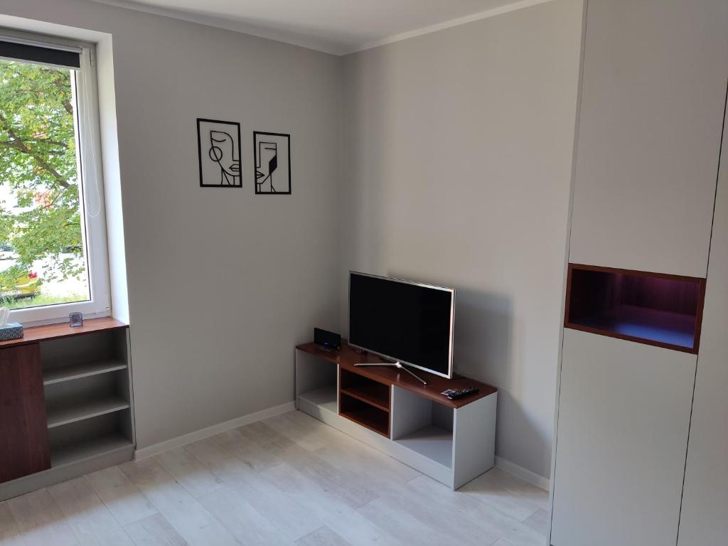 a living room with a television on a desk and a window at Apartament Curie in Zabrze