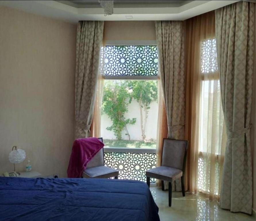 a bedroom with a bed and a window and a chair at Juman B&B in Seeb