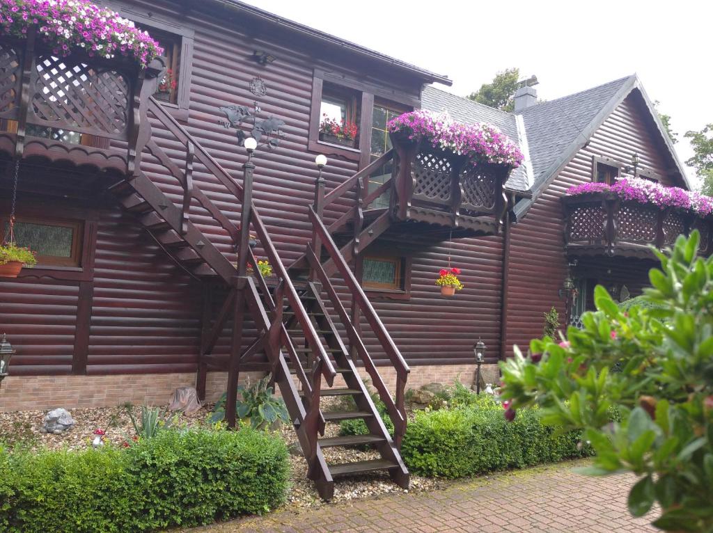drewniany dom z drewnianymi schodami i skrzyniami kwiatowymi w obiekcie Apartmán SMRČEK w mieście Nové Město pod Smrkem