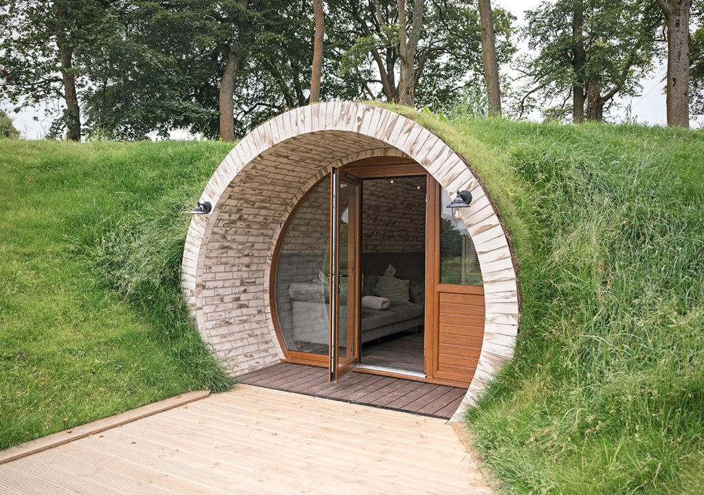 un bâtiment circulaire avec une porte dans l'herbe dans l'établissement Pirnie Lodge Holiday Lets, à Slamannan