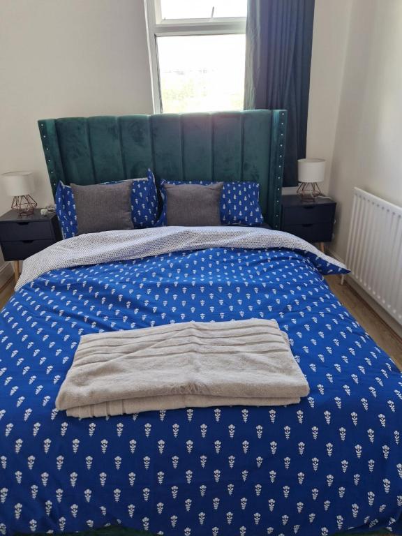 a bed with a blue and white blanket on it at A lovely one bedroom in Hither Green lane in London