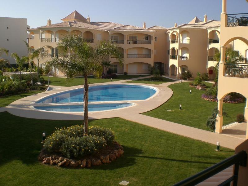 un grand bâtiment avec une piscine dans une cour dans l'établissement Praia Village AG, à Vilamoura