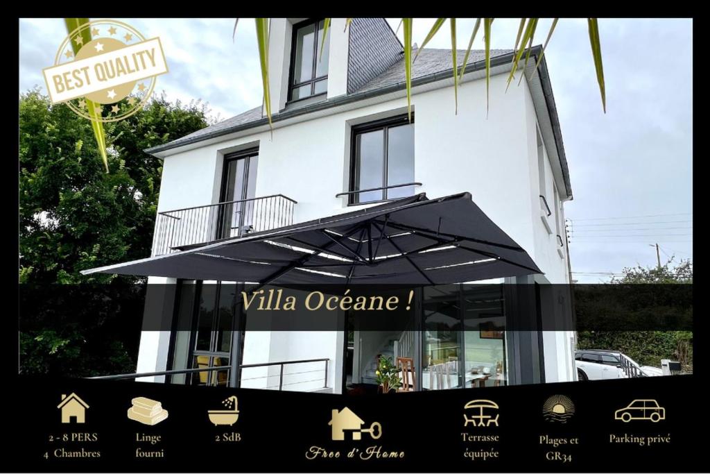 - un bâtiment blanc avec un parasol devant dans l'établissement La Villa Océane, Elegante, Plages, GR34, 2-8 pers, à Clohars-Carnoët