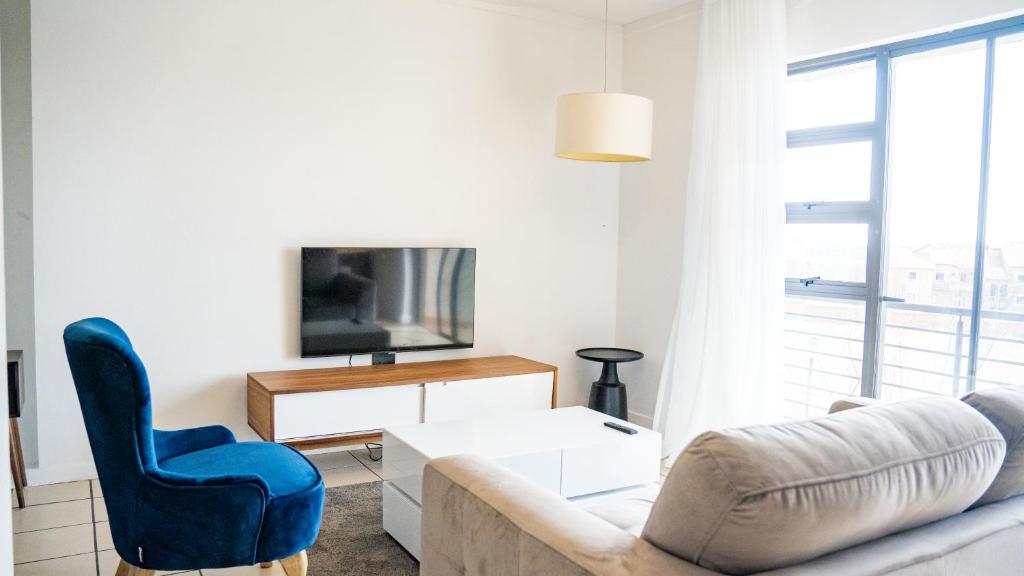a living room with a couch and a tv at Lush Studio Apartment with Back-Up Power. in Sandton
