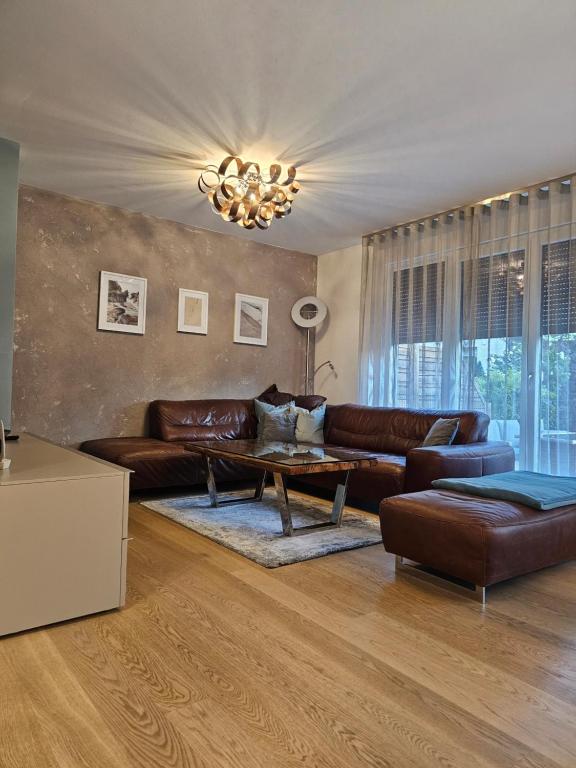 a living room with a leather couch and a table at Cosy & elegant Cityhouse with garden in Vienna