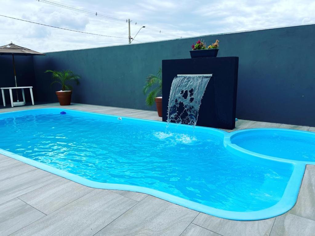 uma grande piscina azul com uma fonte de água em JOTA Área de Lazer em Dourados
