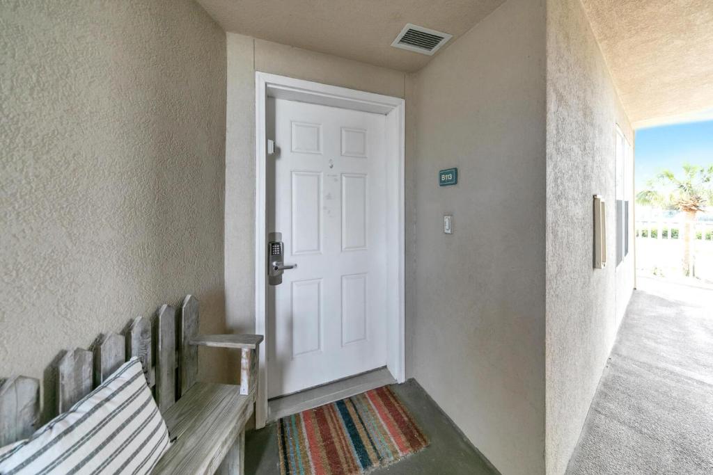 einen Flur mit einer weißen Tür und einer Bank in der Unterkunft Amalfi Coast 113B - Steps from the Beach 2BD 2BA in Destin