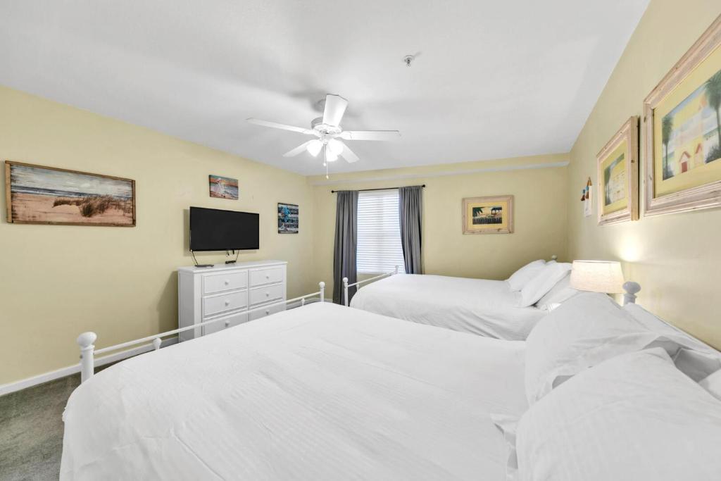 ein Schlafzimmer mit zwei Betten und einem Flachbildfernseher in der Unterkunft Amalfi Coast 113B - Steps from the Beach 2BD 2BA in Destin