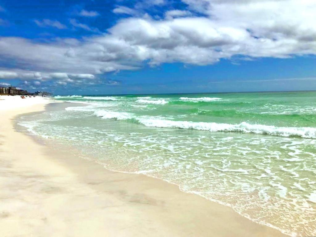 einen Sandstrand mit Meer und Wolken im Himmel in der Unterkunft Biglows Bungalow - About a quarter mile to PRIVATE Neighborhood Beach Access, Pet Friendly, Community Pool in Destin