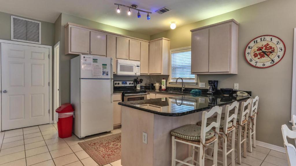 eine Küche mit einem Kühlschrank und einer Theke mit Barhockern in der Unterkunft Biglows Bungalow - About a quarter mile to PRIVATE Neighborhood Beach Access, Pet Friendly, Community Pool in Destin