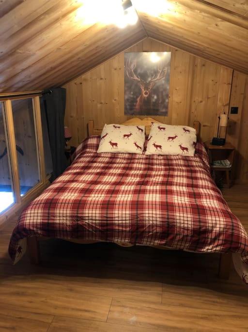 a bed with a plaid blanket and pillows in a room at Chalet au pied des pistes du Cambre d Aze in Saint-Pierre-dels-Forcats