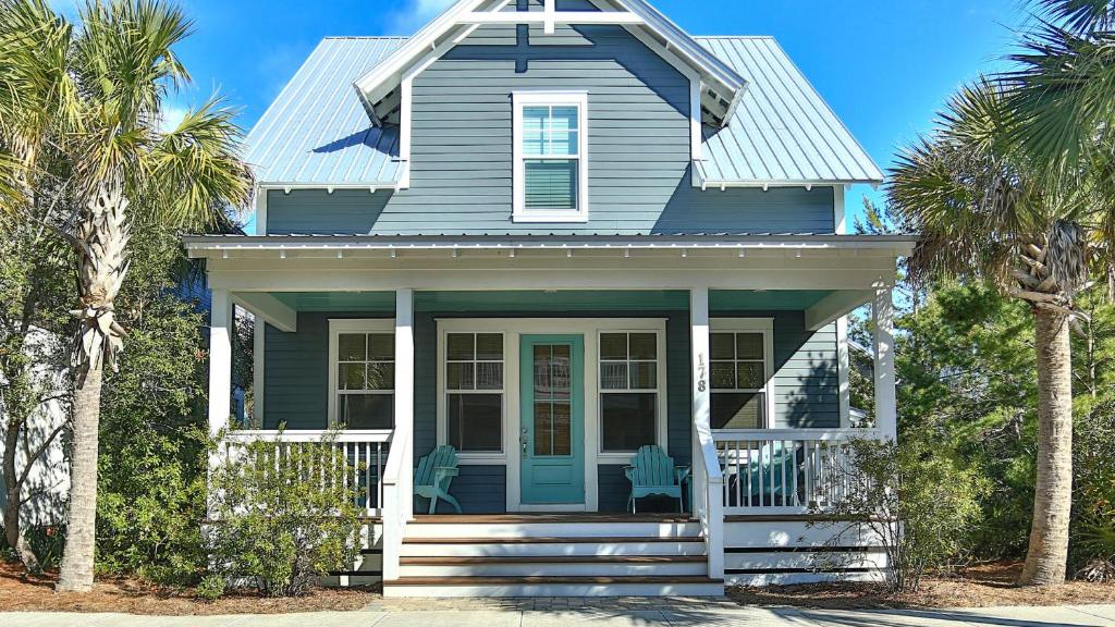 a blue house with palm trees in front of it at Family Ties - Located in Seacrest Beach 2 Master bedrooms and a large communal pool in Rosemary Beach