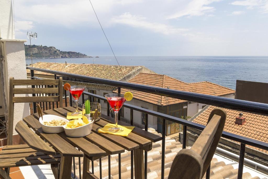 a wooden table with drinks and snacks on a balcony at Zina Suite Apartment in Giardini Naxos