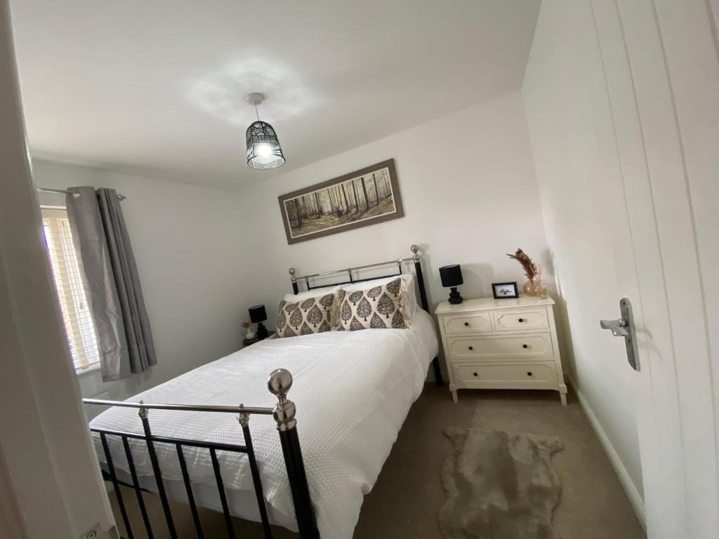 a bedroom with a bed and a dresser and a window at The Belfry 3 Bedrooms 2 Bathrooms Contractors & Family in Higham Ferrers