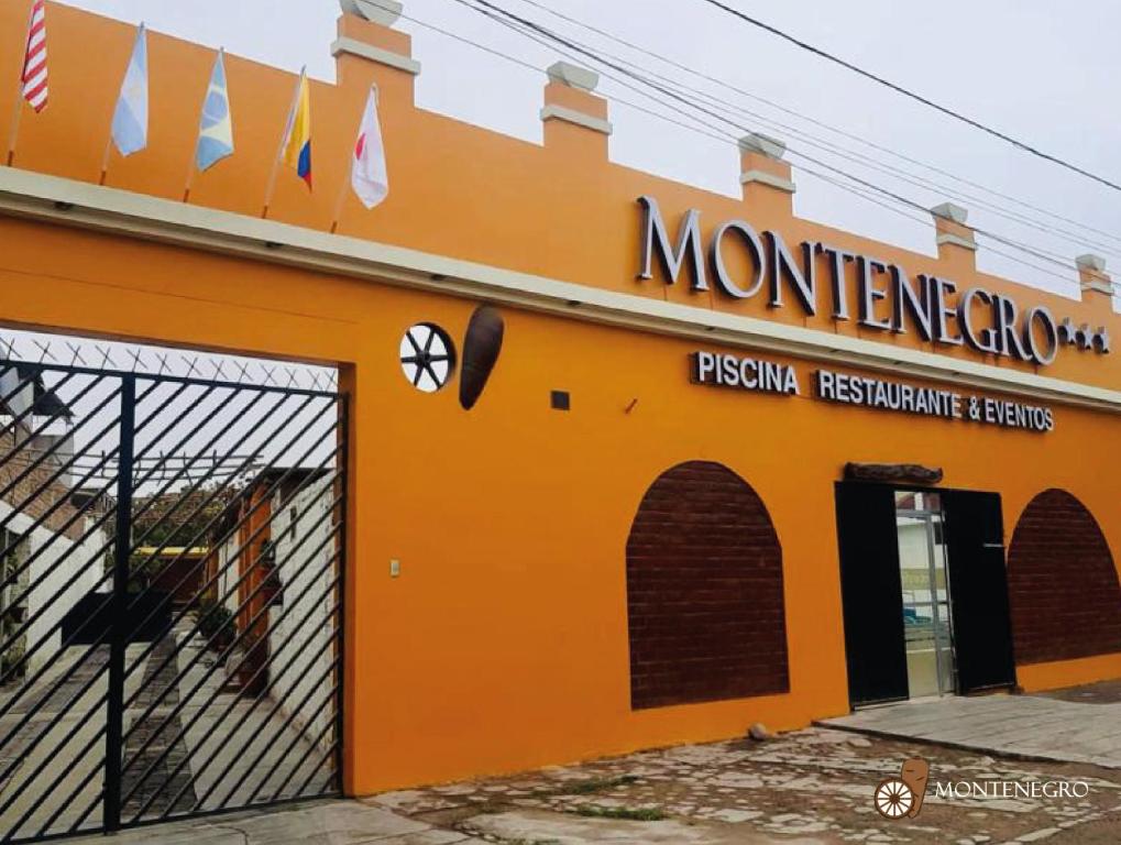 イカにあるHospedaje Montenegroのレストランの看板付きのオレンジ色の建物