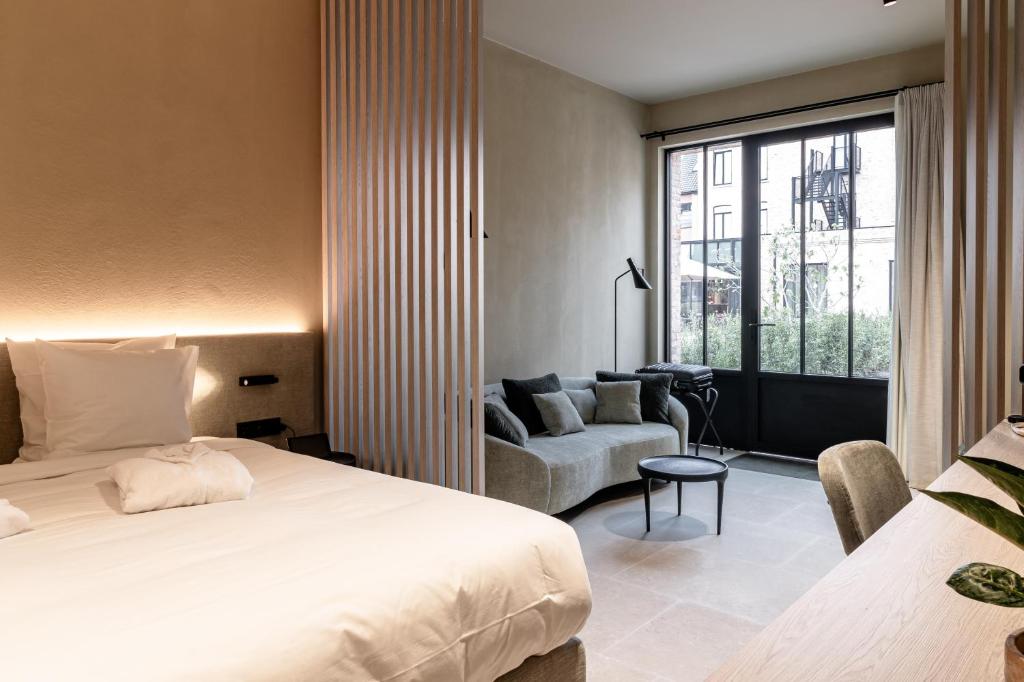 een slaapkamer met een bed, een bank en een raam bij Hotel T in Waregem