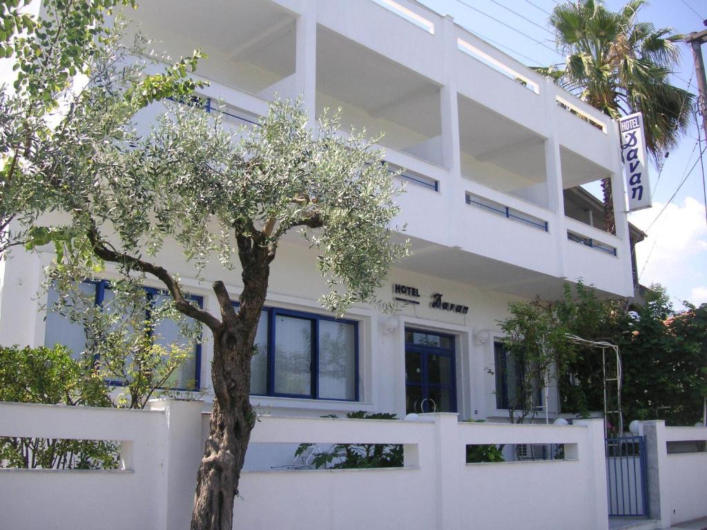 um edifício branco com uma árvore em frente em Danae Hotel em Limenas