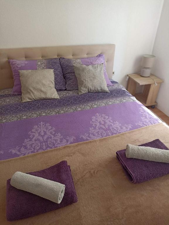 a bed with purple sheets and two towels on it at Sleep & fly - Single room with shared bathroom in Sarajevo