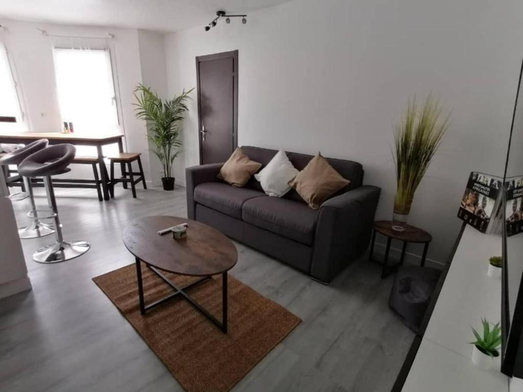 a living room with a couch and a table at Appartement Paris Roissy Astérix in Louvres