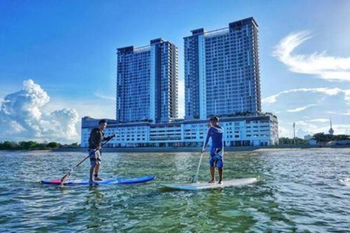 two men are standing on paddle boards in the water at Kuantan Imperium Residence Cityview With Netflix in Kuantan