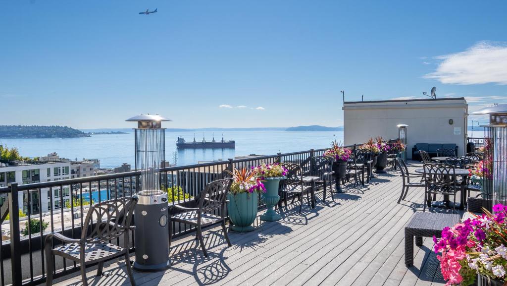 uma varanda com mesas e cadeiras e vista para a água em The Mediterranean Inn em Seattle