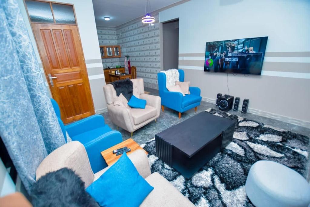 a living room with blue chairs and a tv at Pai4 Apartments 2 in Dodoma