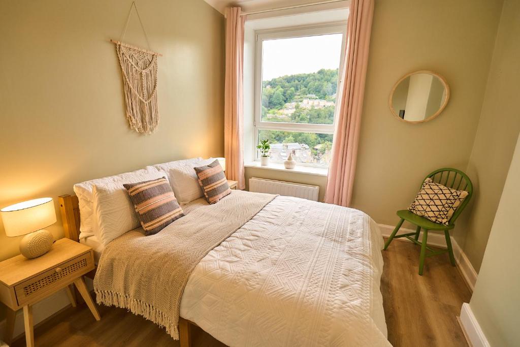 a bedroom with a bed and a window and a chair at Wood End View - Traditional Top-and-Bottom House in Hebden Bridge