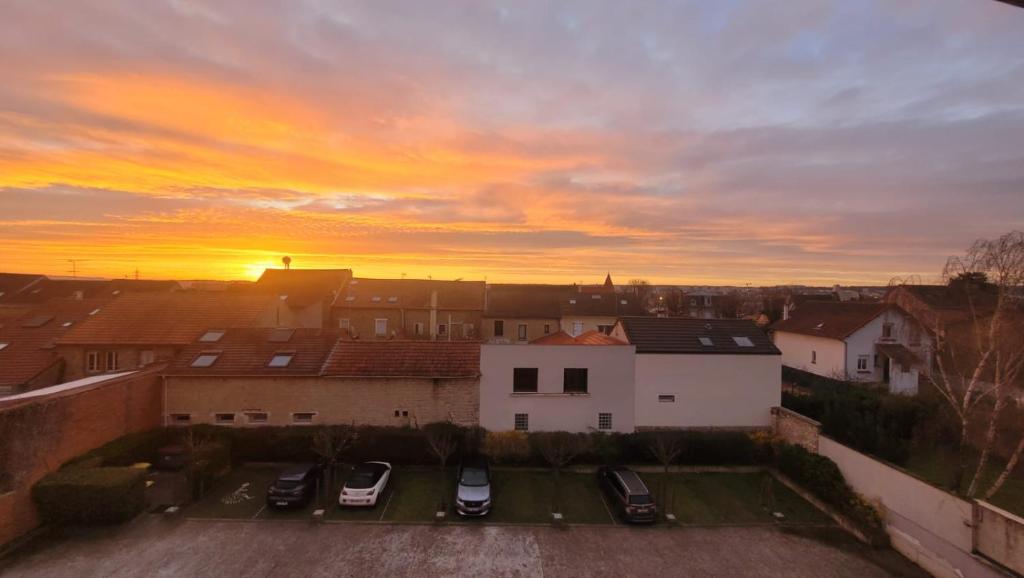 ein Sonnenuntergang über einer Stadt mit Autos auf einem Parkplatz in der Unterkunft Cosy Home Paris in Carrières-sous-Poissy