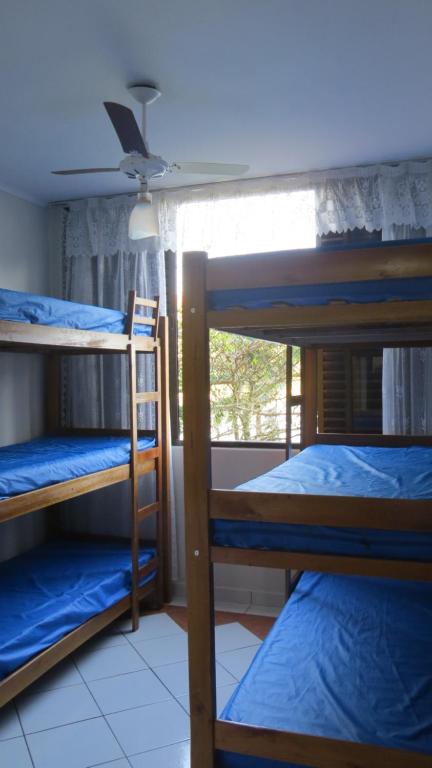 a room with three bunk beds and a window at Apartamento Pé na Areia in Caraguatatuba