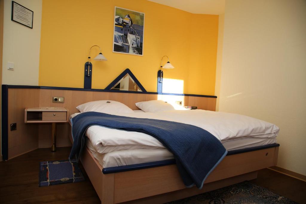 sypialnia z dużym łóżkiem z żółtymi ścianami w obiekcie Gasthaus-Pension Islekhöhe Gansen w mieście Krautscheid