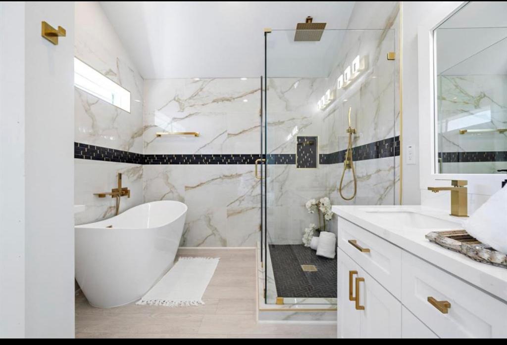 y baño con bañera y ducha acristalada. en Villa De Briley en Houston