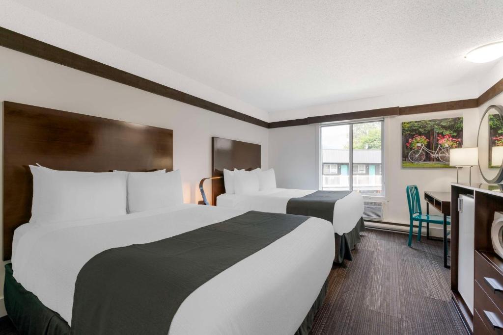 a hotel room with two beds and a desk at Stoke Hotel SureStay Collection by Best Western in Revelstoke